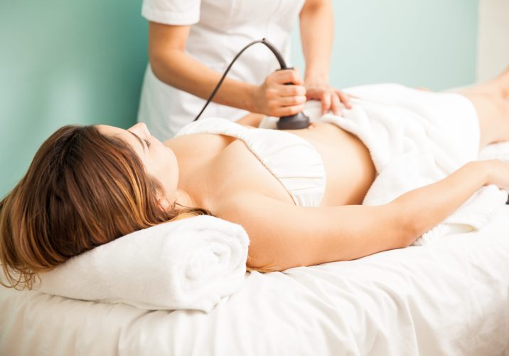 Female therapist giving a reductive and reaffirming treatment to a client and focusing on her belly